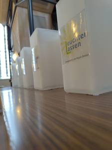 Ikea-Lampen, die einen Aufkleber haben, auf dem Steht: "Leuchten Lassen" im Hintergrund der Schrift ist eine Sonne